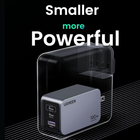 UGREEN 100W portable power bank in a sleek silver-gray finish with a black USB-C port panel, shown inside a transparent protective case on a black background with promotional text reading 'Smaller more Powerful'.